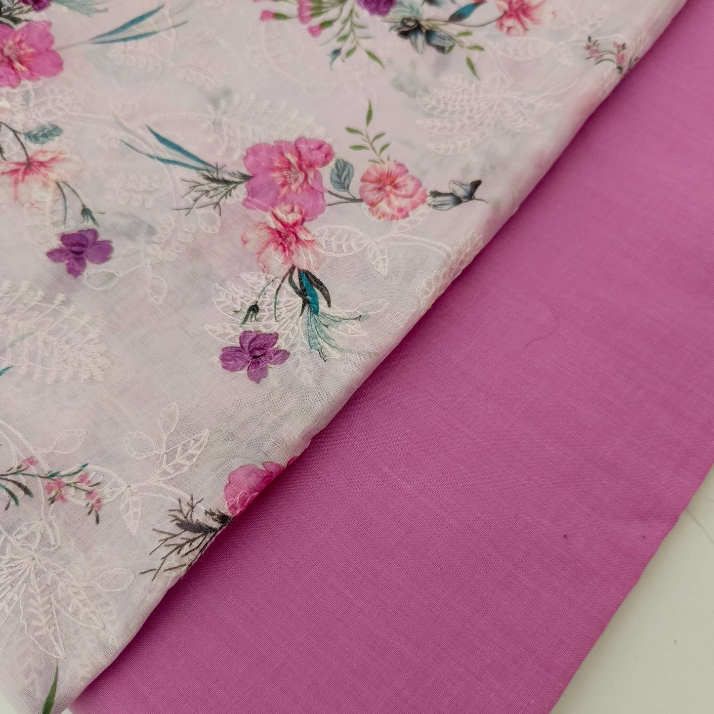 Floral fabric with pink flowers and green leaves on a pink background
