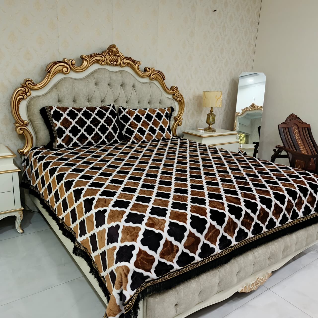 Bed with decorative headboard and patterned blanket in a bedroom setting