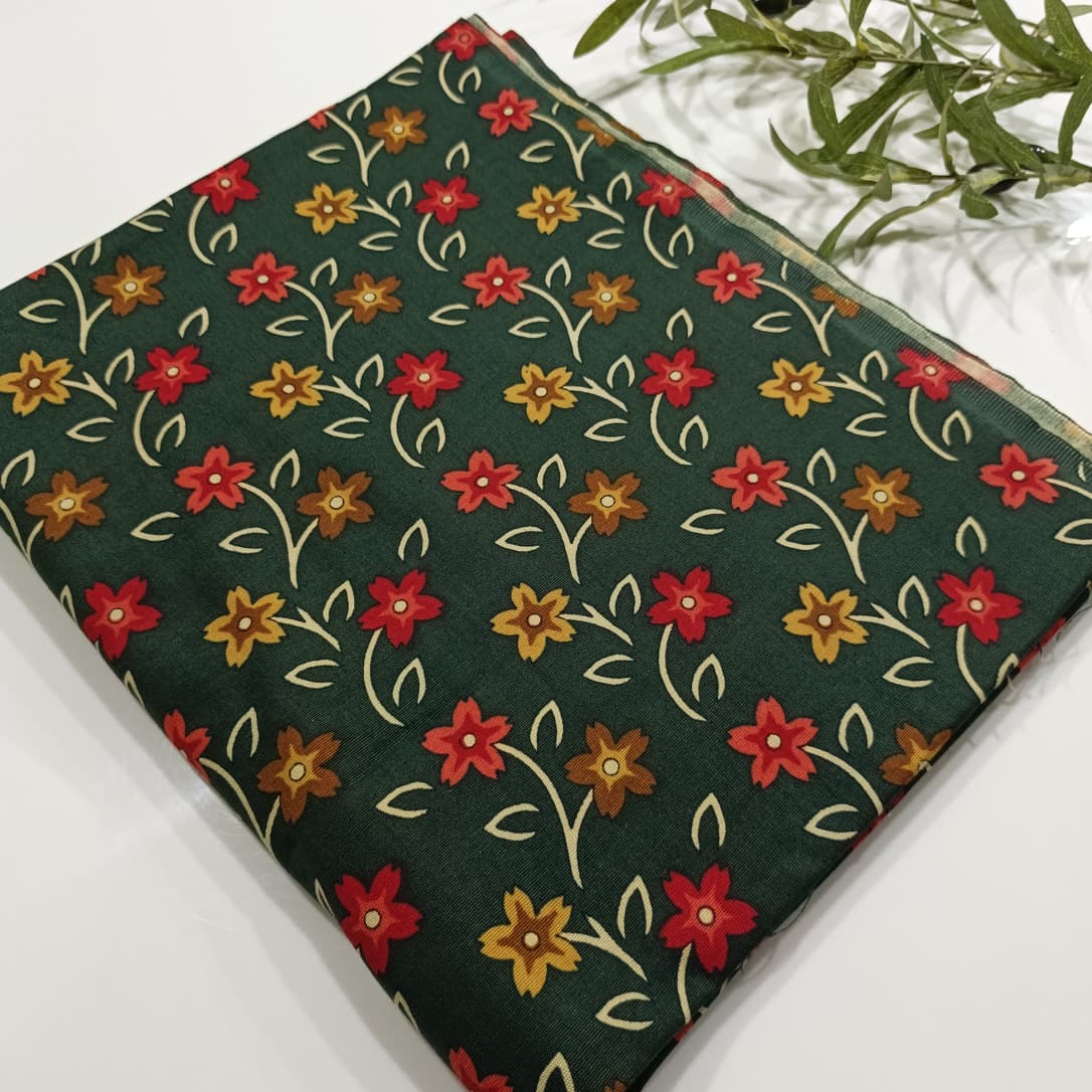 Floral patterned fabric with red, yellow, and orange flowers on a green background.