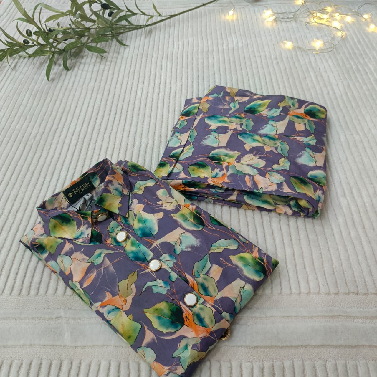 Folded fabric with a floral pattern on a textured surface with lights and leaves.
Celebrate Eid with Noor-e-Zar Collection - Flat 25% Off Festive Pakistani Dresses Online