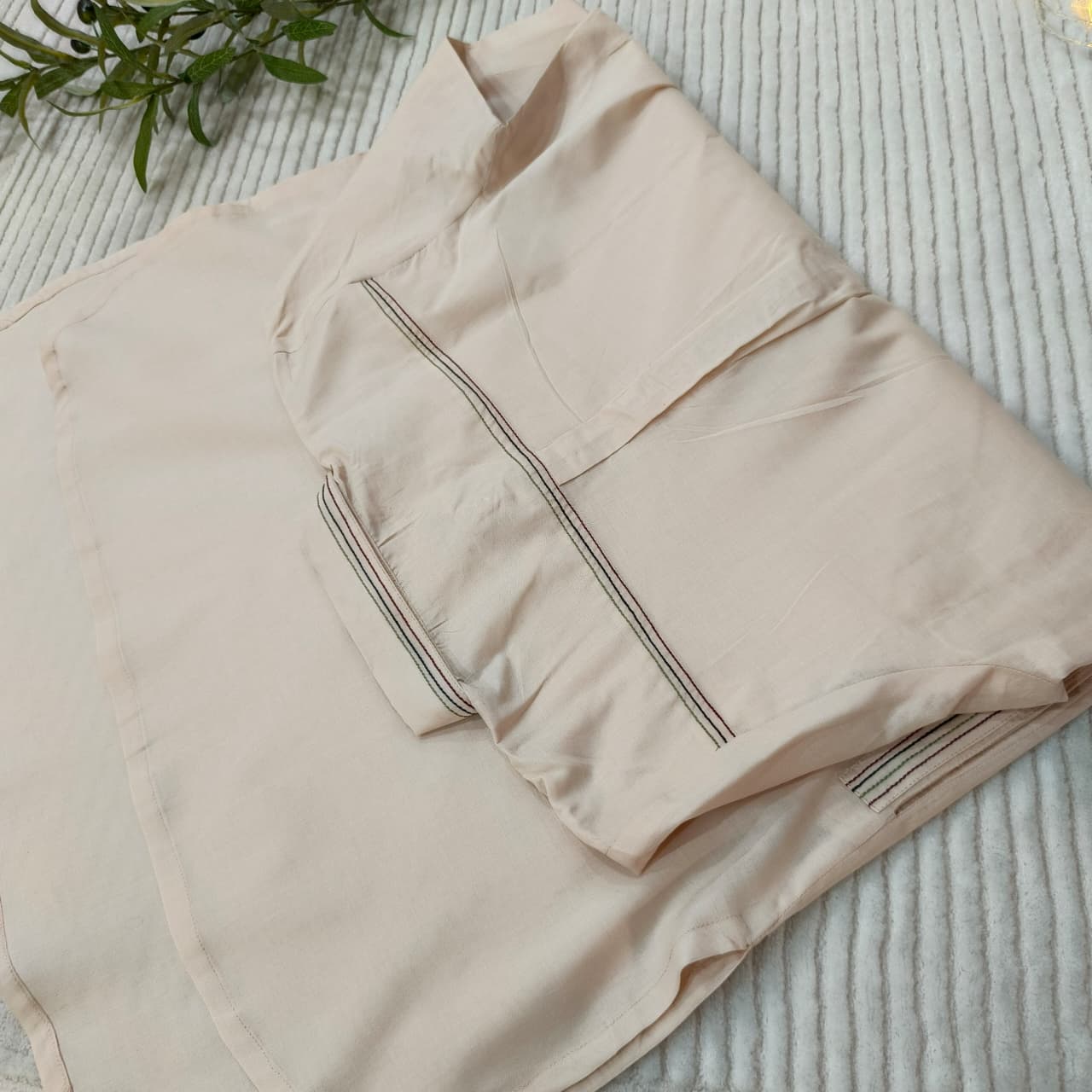 Beige quilted jacket on a textured surface with greenery in the corner