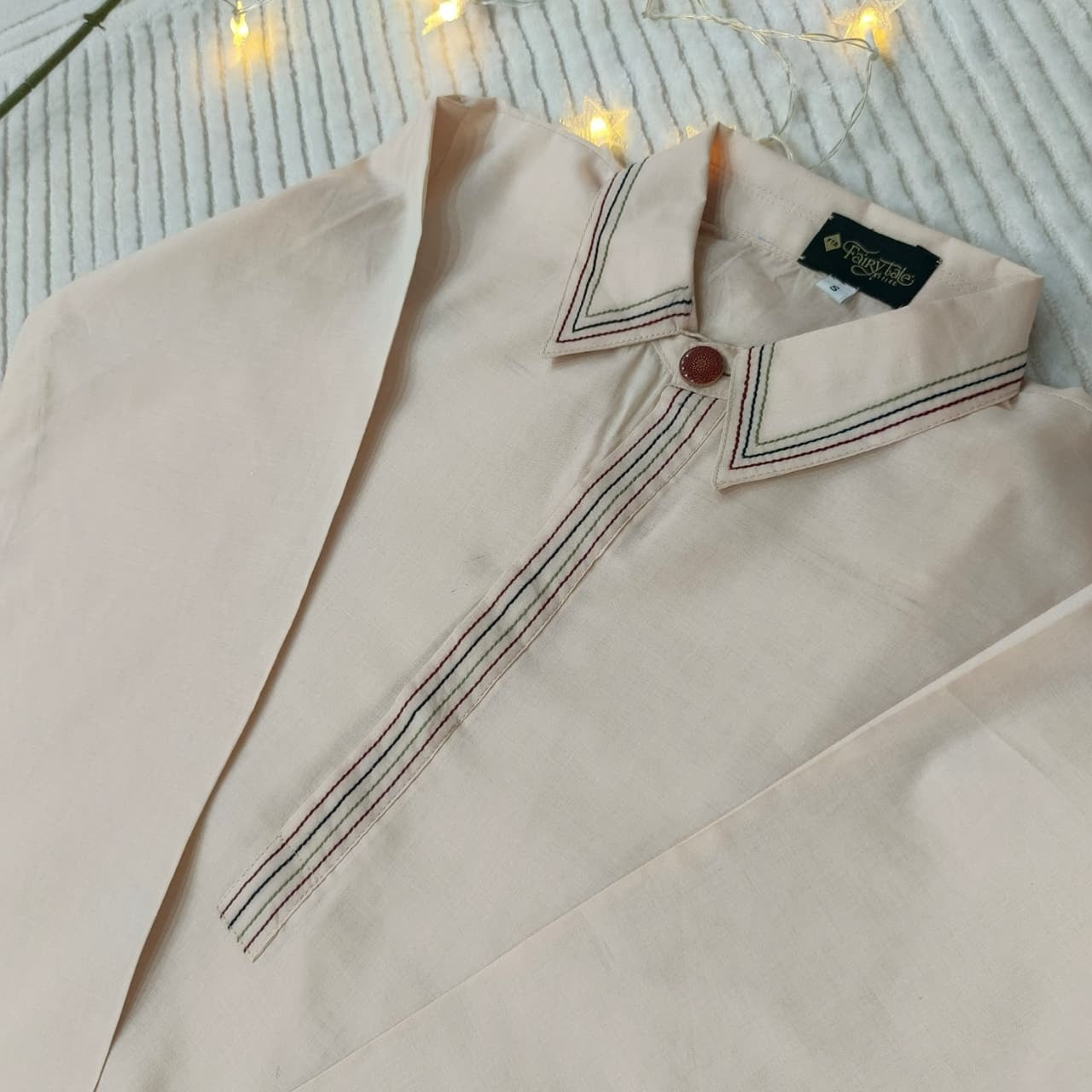 Beige shirt with collar and button on a textured surface