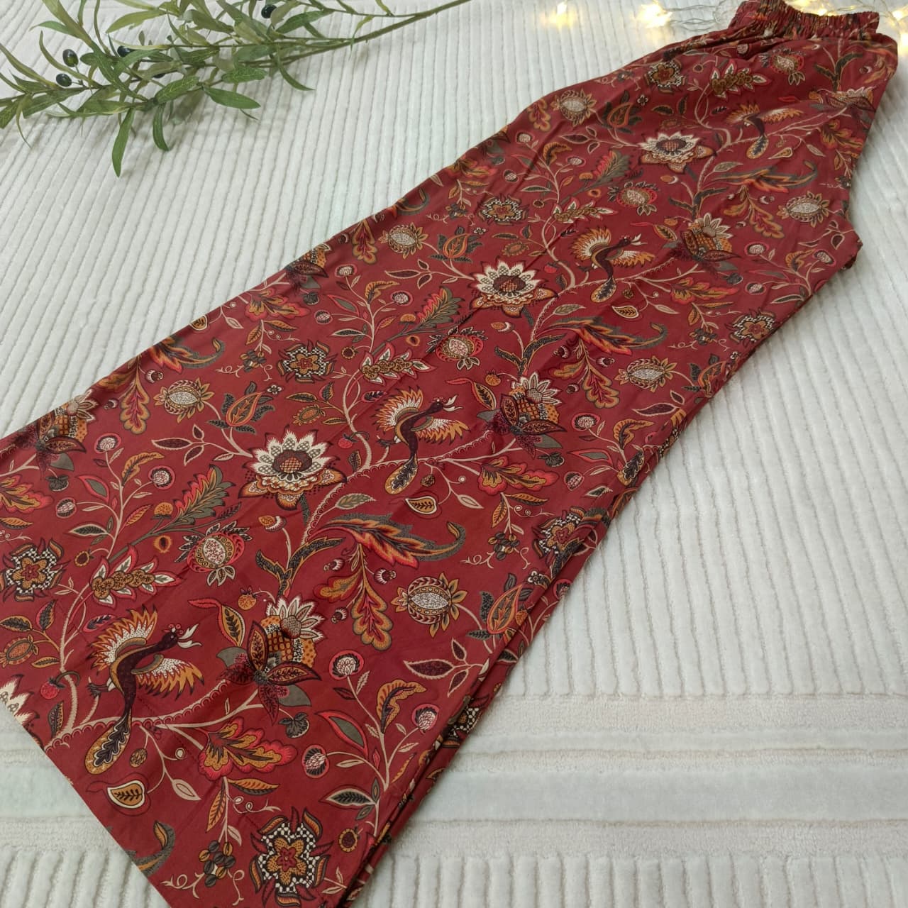 Red patterned fabric on a textured surface with a plant in the corner