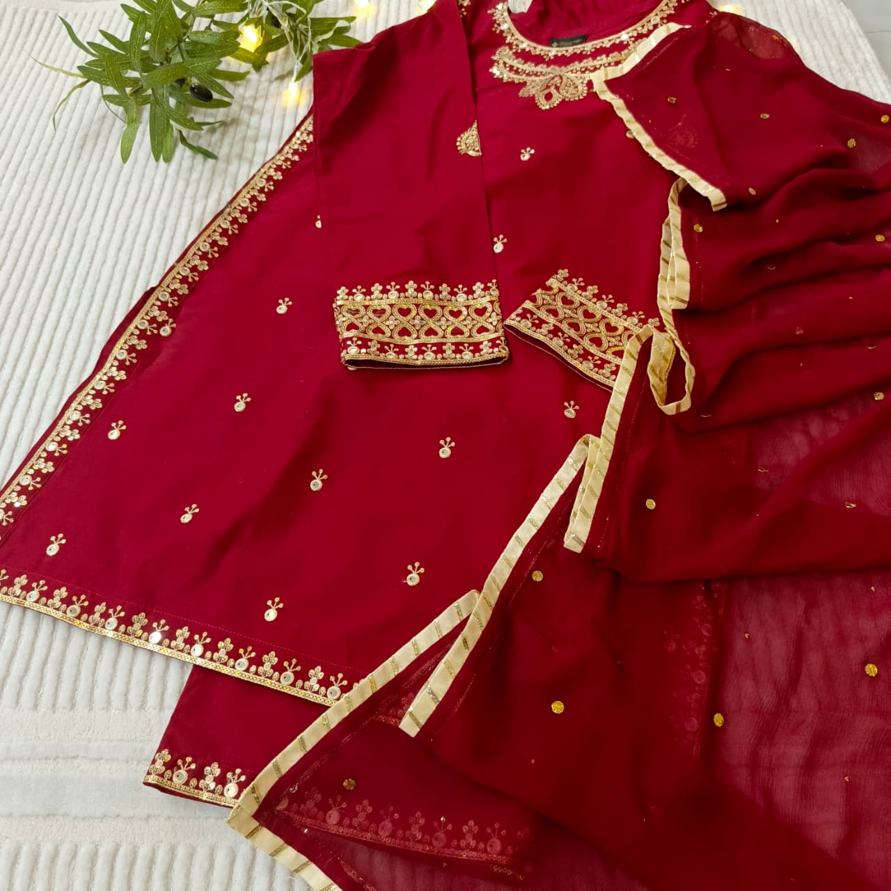 maroon sequence with gold embroidery on a white surface