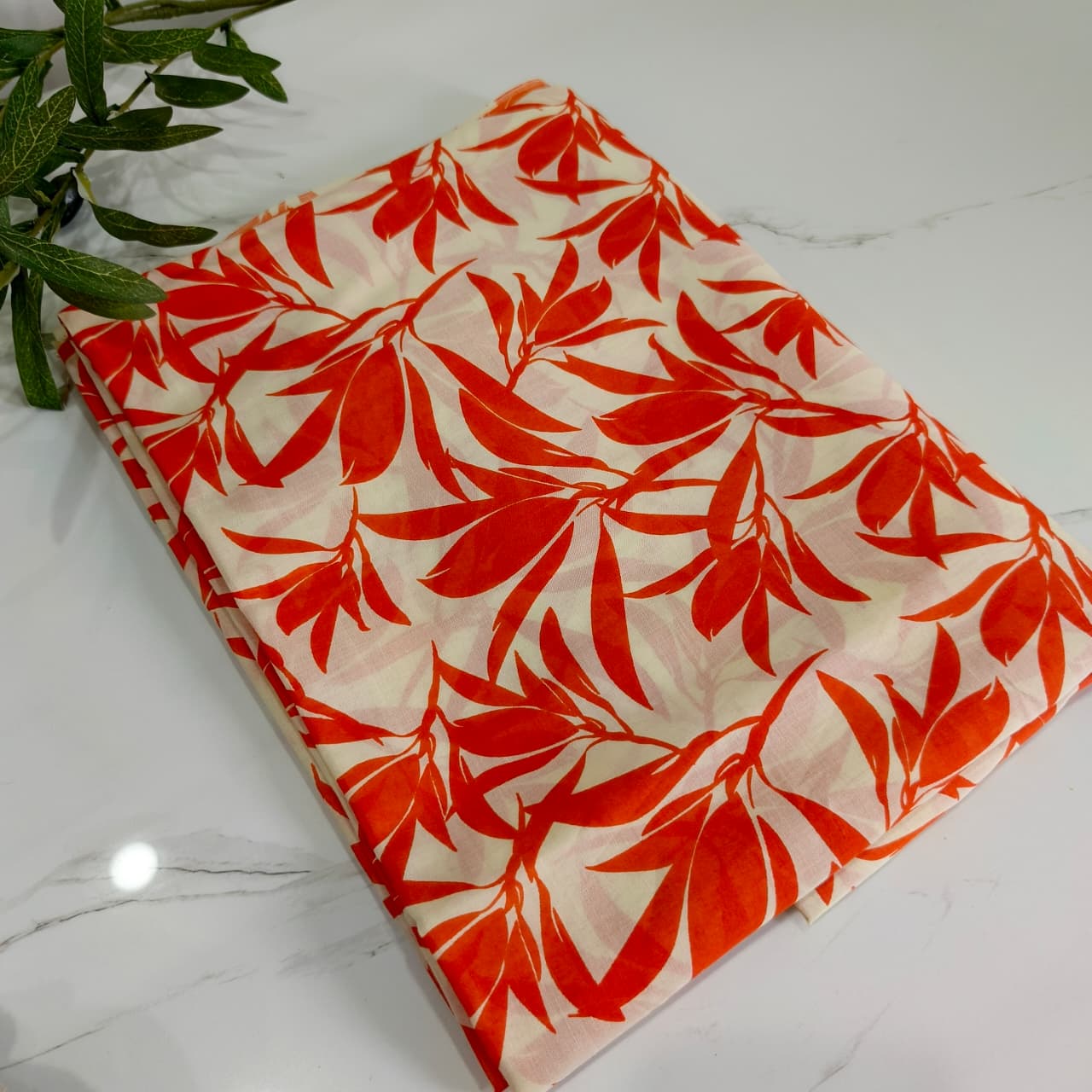 orange leaf patterned fabric on a white marble surface