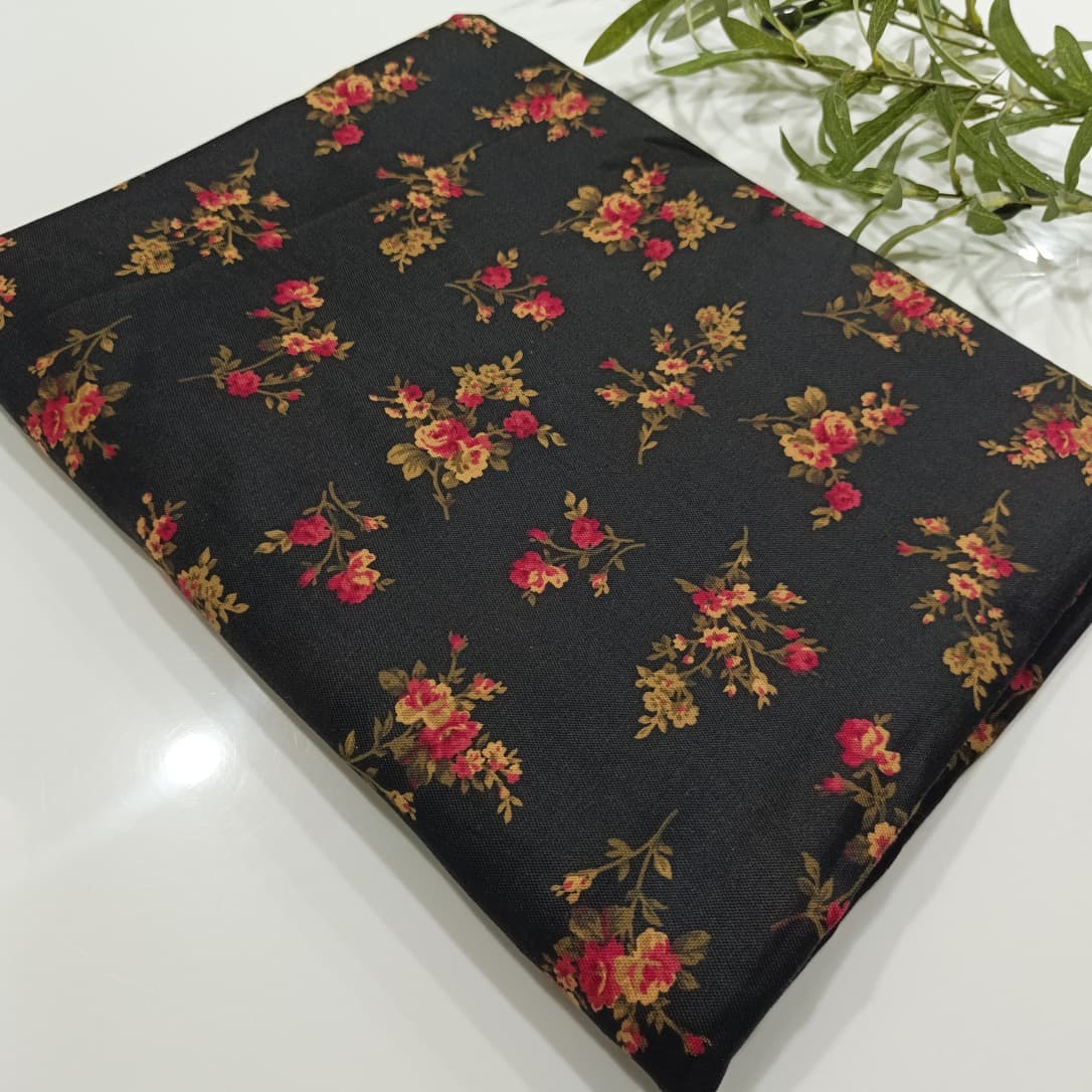 Floral-patterned fabric on a black background with greenery.