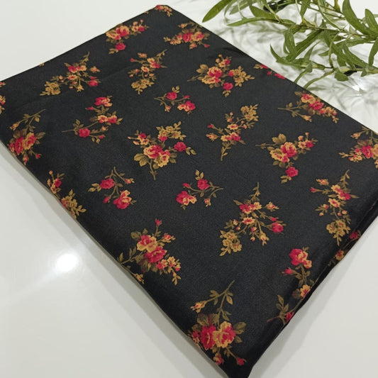 Floral-patterned fabric on a black background with greenery.