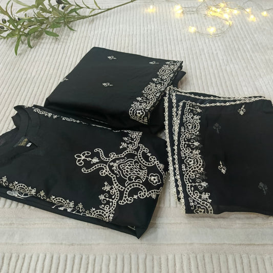 Black fabric with silver embroidery on a textured surface with greenery and lights.
Celebrate Eid with Noor-e-Zar Collection - Flat 25% Off Festive Pakistani Dresses Online