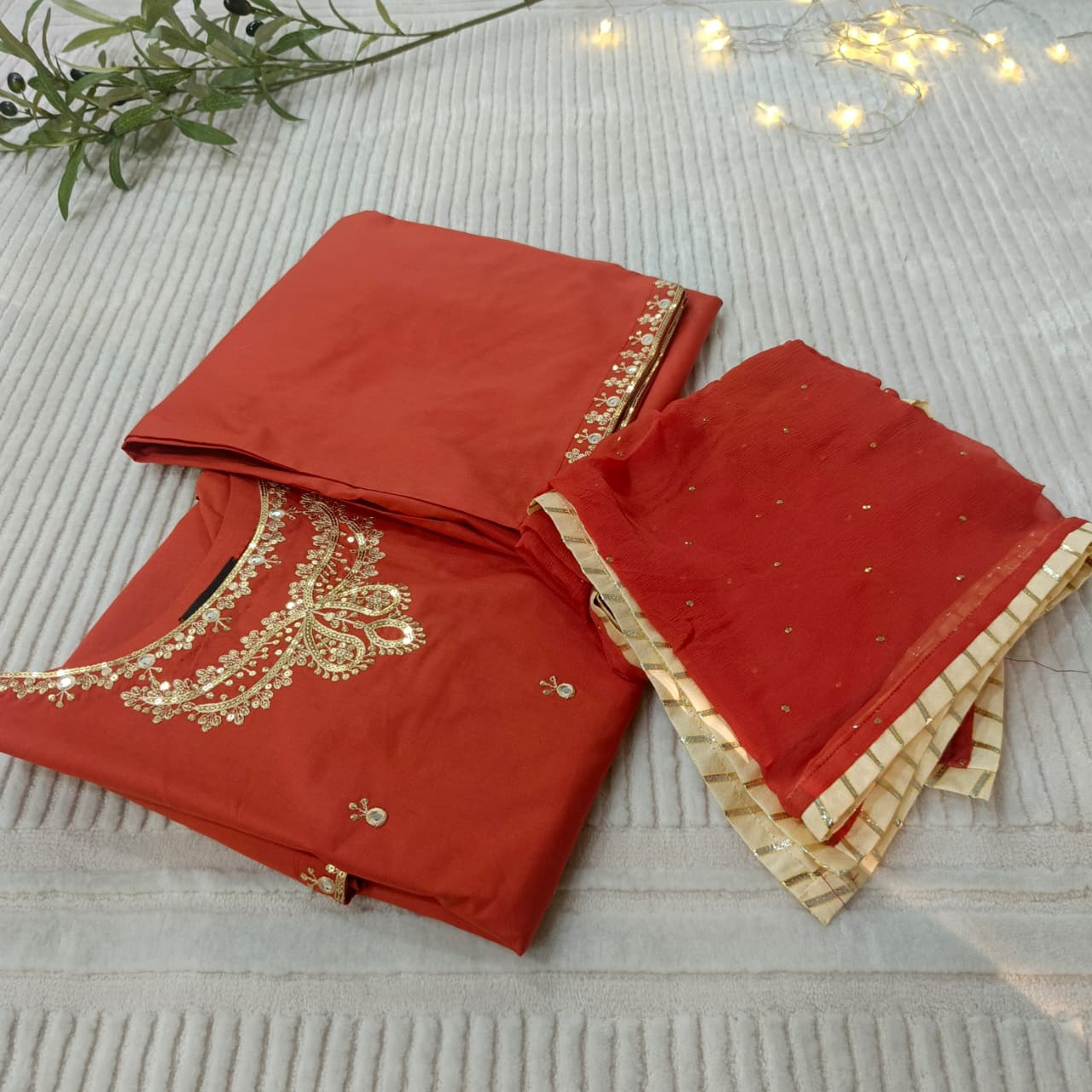 Rust suit with gold embroidery on a textured surface
