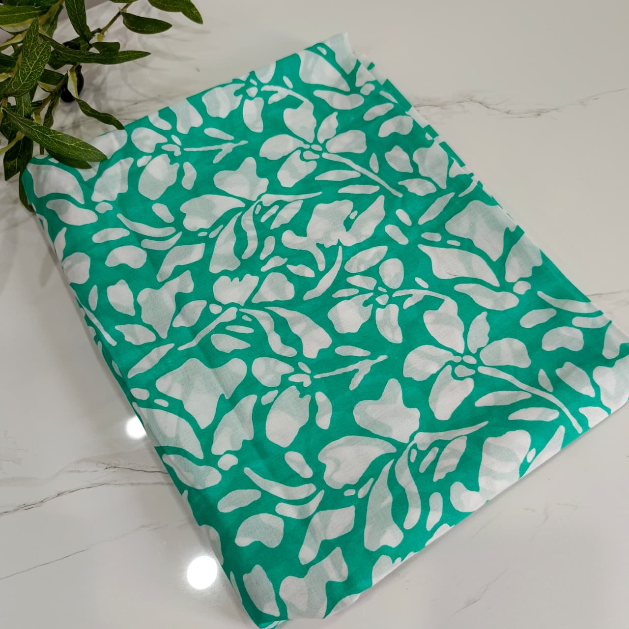 Teal fabric with white floral pattern on a marble surface