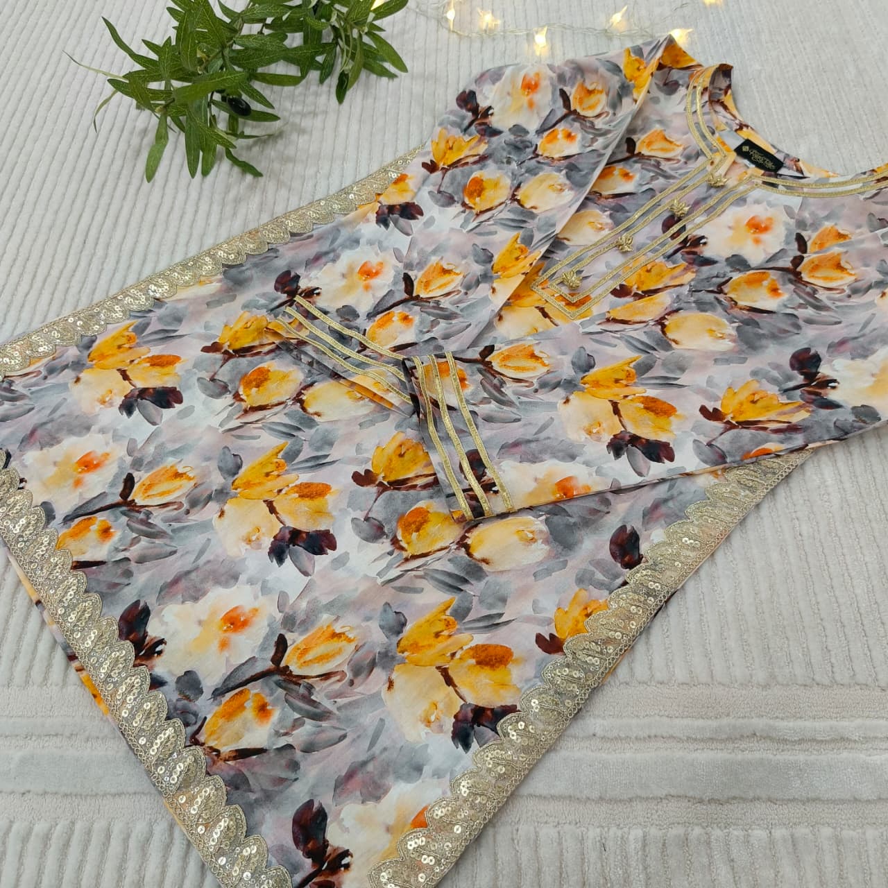 Floral patterned fabric with gold border on a textured surface
Celebrate Eid with Noor-e-Zar Collection - Flat 25% Off Festive Pakistani Dresses Online